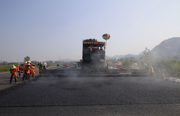 2019年8月，宜春經(jīng)開(kāi)區(qū)S311路面攤鋪現(xiàn)場(chǎng)，工友們輔助路面兩側(cè)的分料、補(bǔ)窩等作業(yè)